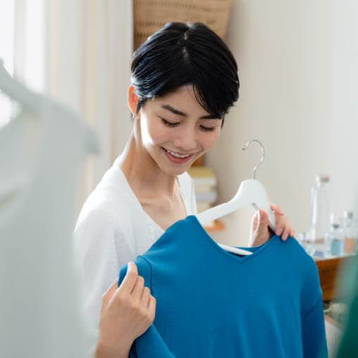 服をハンガーにかけている女性