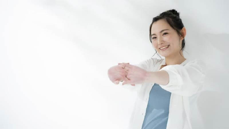 両手を前に出して伸びをしている女性